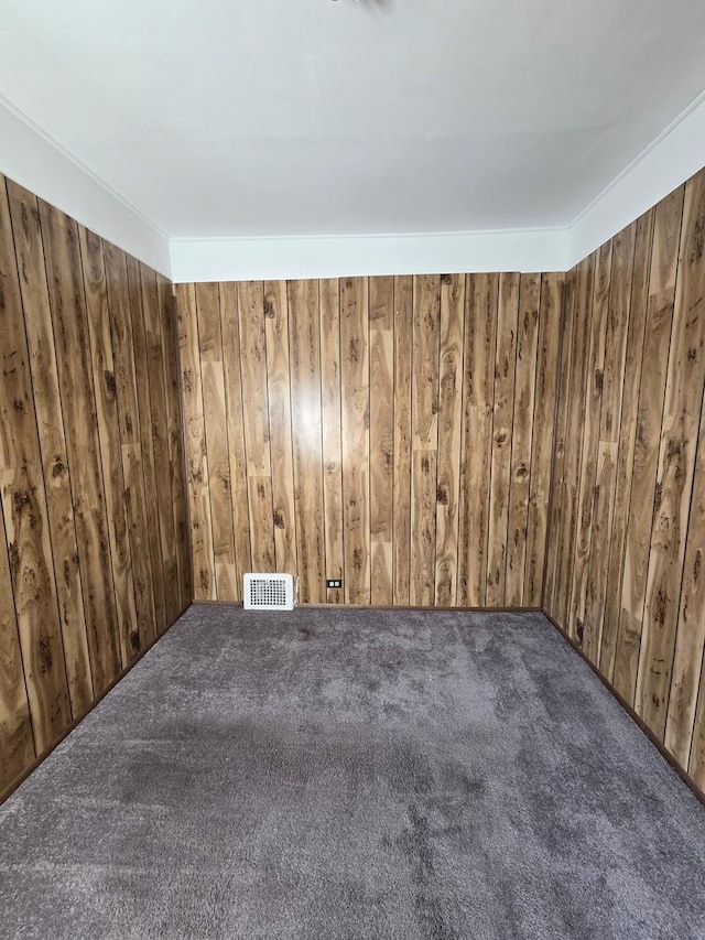 empty room featuring visible vents and wooden walls