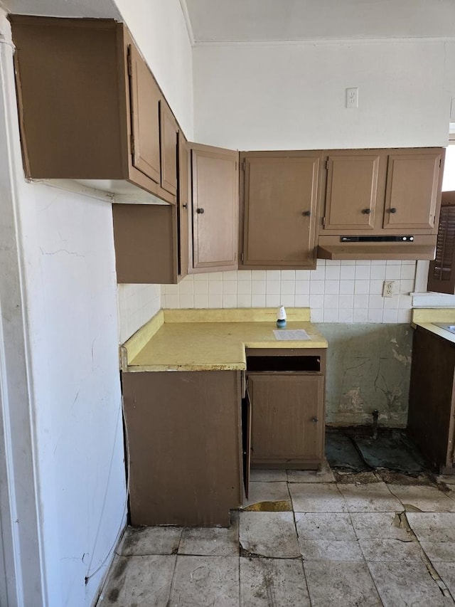 kitchen featuring under cabinet range hood, tasteful backsplash, and light countertops