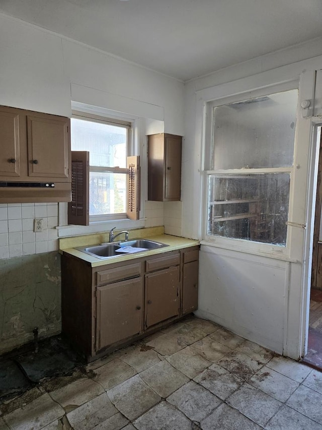 kitchen featuring light countertops, backsplash, a sink, and stone tile flooring