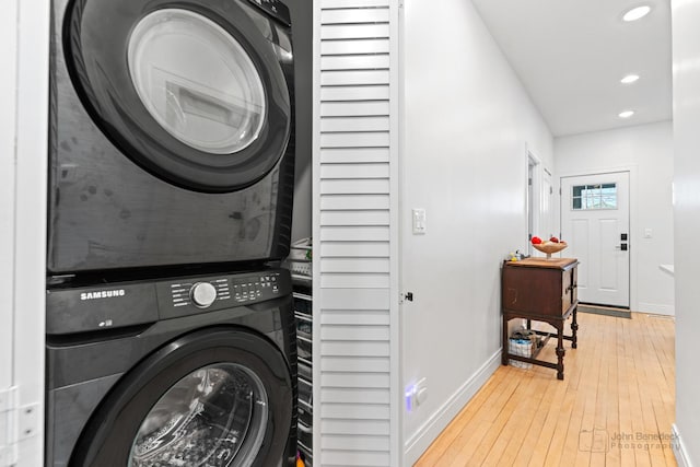 washroom featuring laundry area, baseboards, wood-type flooring, stacked washing maching and dryer, and recessed lighting