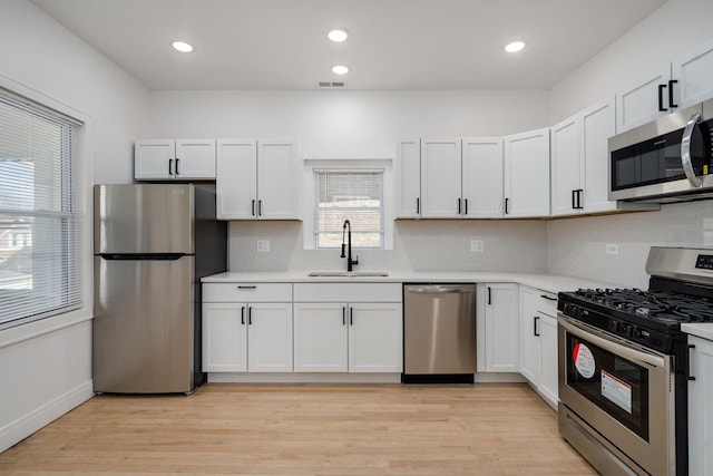 kitchen featuring stainless steel appliances, a sink, visible vents, light countertops, and light wood-type flooring