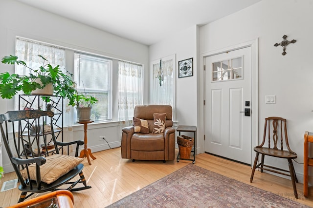 living area featuring visible vents, baseboards, and wood finished floors