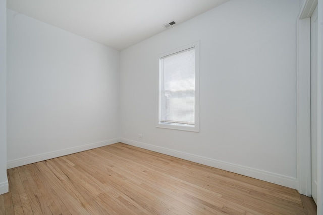 spare room featuring light wood-type flooring, visible vents, and baseboards