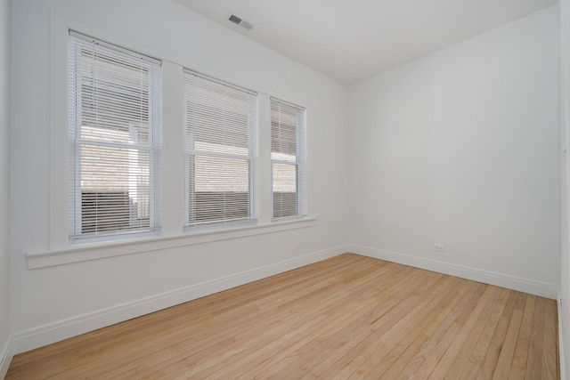 empty room featuring visible vents, light wood-style flooring, and baseboards