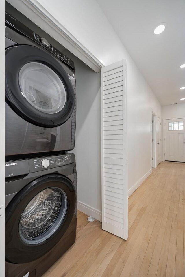 laundry room with stacked washer / dryer, laundry area, baseboards, and hardwood / wood-style floors