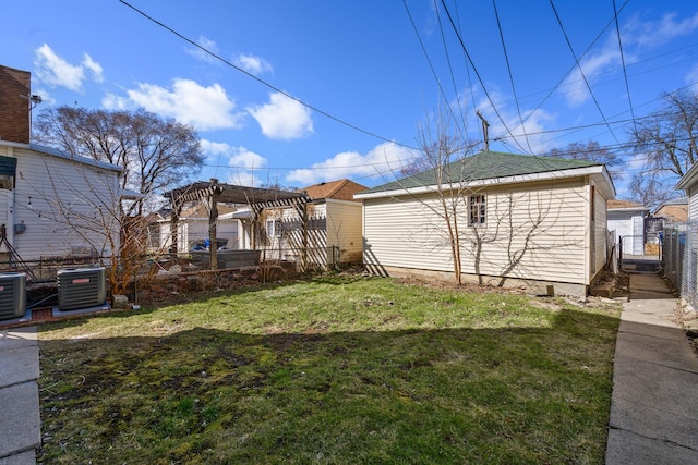 rear view of house featuring an outbuilding, fence, a yard, central AC, and a pergola