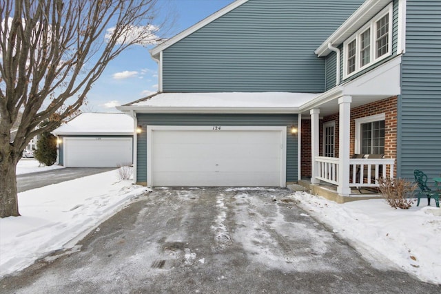 snow covered property featuring an attached garage and brick siding