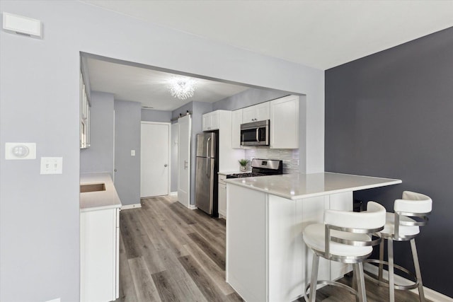 kitchen with stainless steel appliances, a barn door, white cabinets, a peninsula, and a kitchen breakfast bar