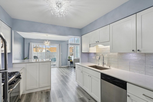 kitchen featuring light countertops, appliances with stainless steel finishes, white cabinets, a sink, and a chandelier