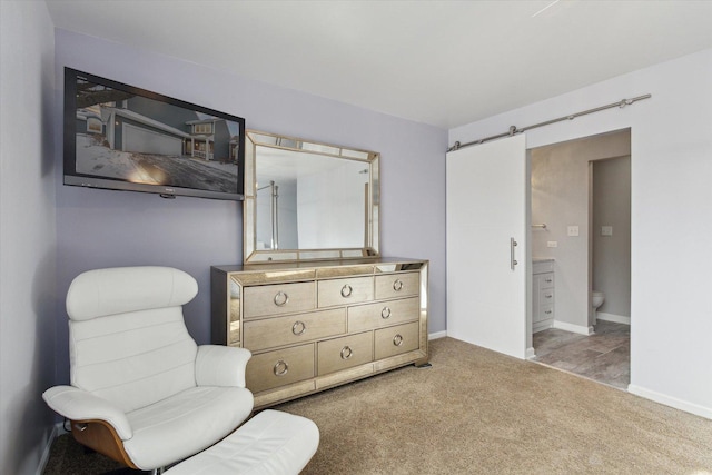 sitting room featuring light colored carpet, baseboards, and a barn door