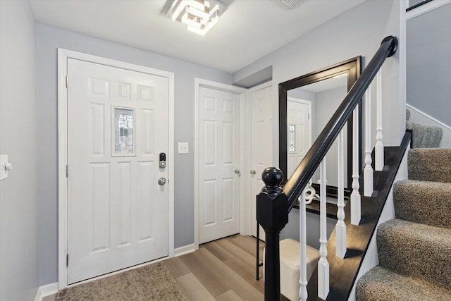 foyer entrance featuring stairway, baseboards, and wood finished floors