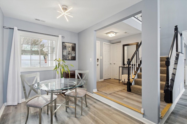 dining space with stairs, wood finished floors, visible vents, and baseboards