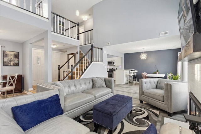 living area featuring light wood-type flooring, visible vents, stairway, and a chandelier