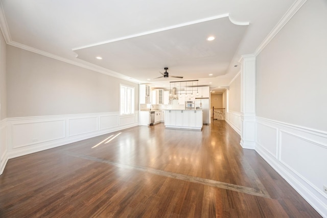 unfurnished living room with arched walkways, recessed lighting, a ceiling fan, ornamental molding, and dark wood finished floors