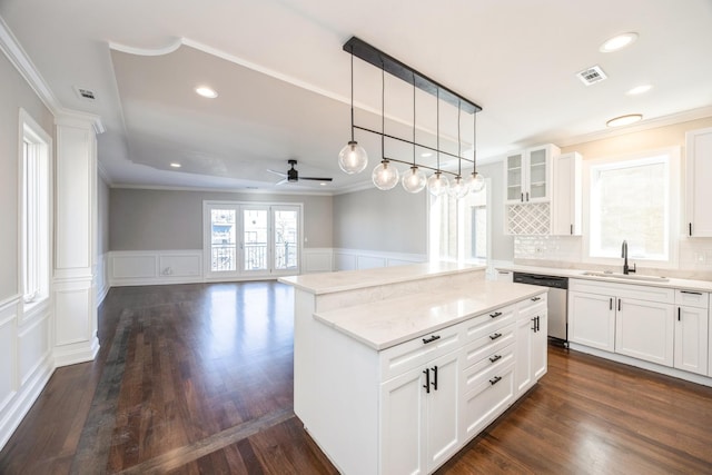 kitchen with dishwasher, glass insert cabinets, open floor plan, white cabinetry, and a sink