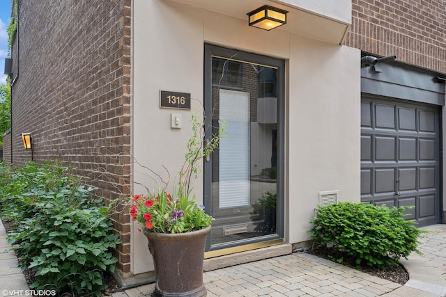 entrance to property featuring brick siding and stucco siding