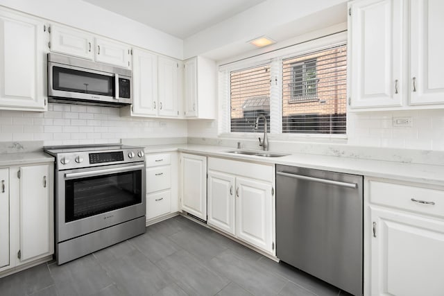 kitchen with appliances with stainless steel finishes, a sink, white cabinetry, and tasteful backsplash