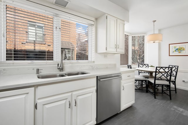 kitchen with light countertops, hanging light fixtures, stainless steel dishwasher, white cabinets, and a sink