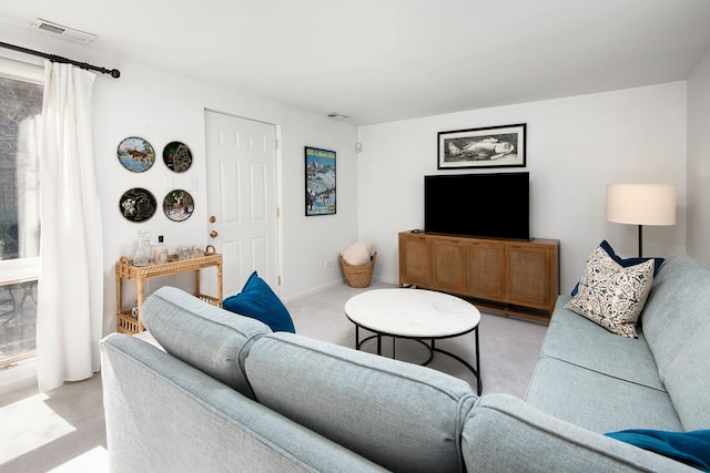 living area with baseboards, visible vents, and light colored carpet