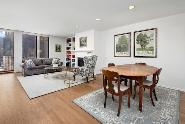 dining space with baseboards, a fireplace, wood finished floors, and recessed lighting