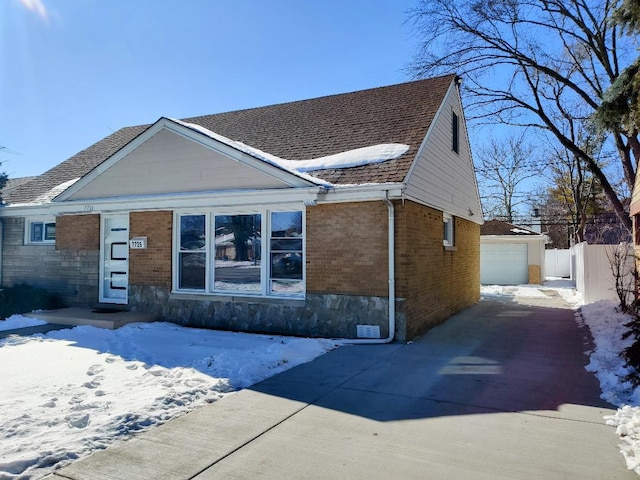 view of front of property with brick siding, a detached garage, fence, an outdoor structure, and driveway