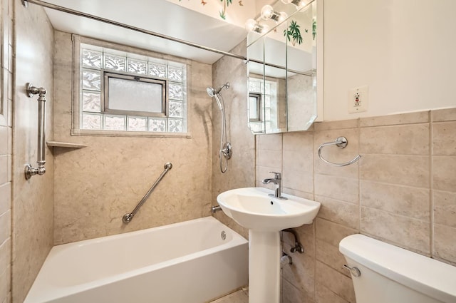 bathroom featuring tub / shower combination, toilet, and tile walls