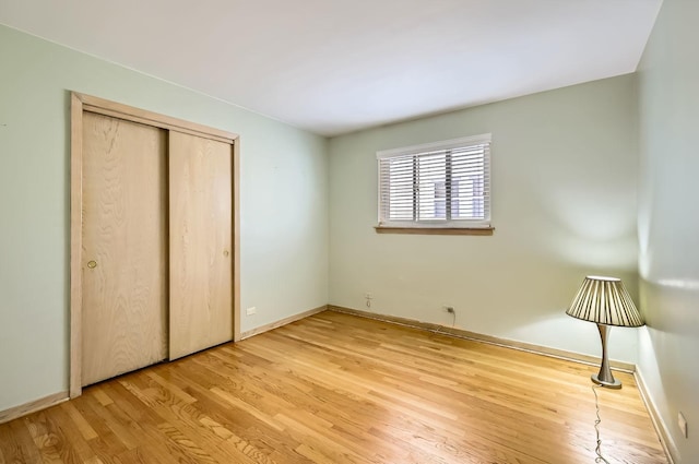 unfurnished bedroom featuring light wood-style flooring, baseboards, and a closet