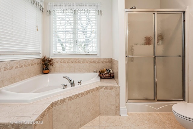 full bathroom featuring tile patterned flooring, toilet, a shower with shower door, and tiled bath