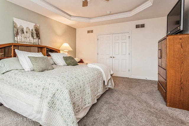 carpeted bedroom with visible vents, a raised ceiling, and ornamental molding