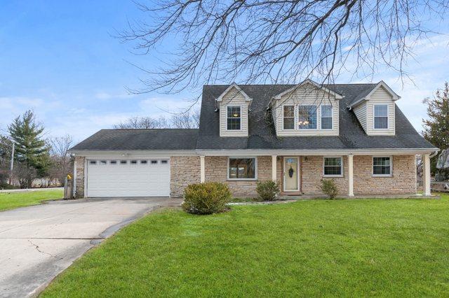 cape cod-style house with a garage, driveway, and a front lawn