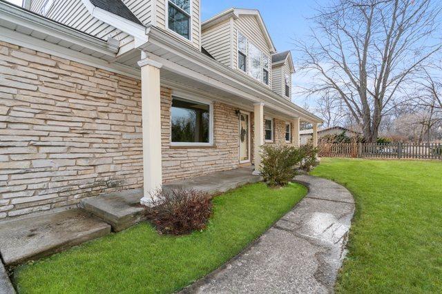 view of side of home with a yard, stone siding, and fence