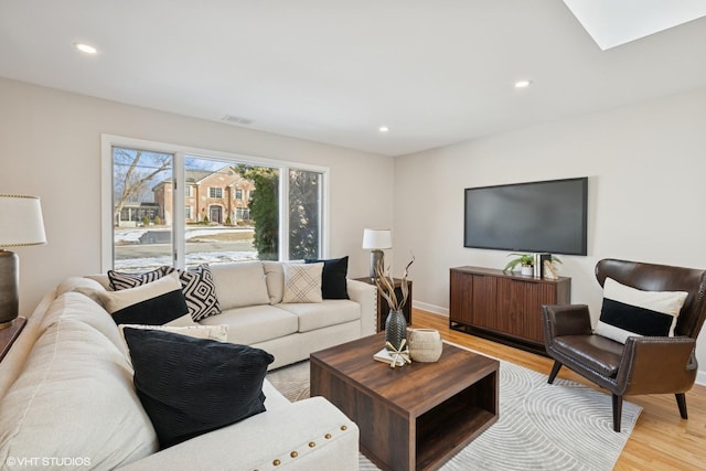 living area with baseboards, light wood finished floors, visible vents, and recessed lighting