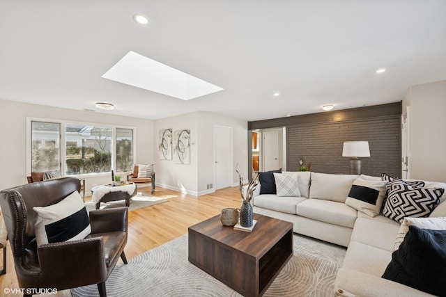 living area with a skylight, baseboards, light wood finished floors, and recessed lighting