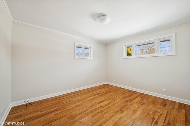 empty room featuring light wood-style floors, crown molding, and baseboards