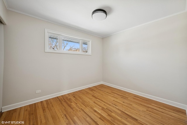 spare room featuring light wood-style flooring, baseboards, and crown molding