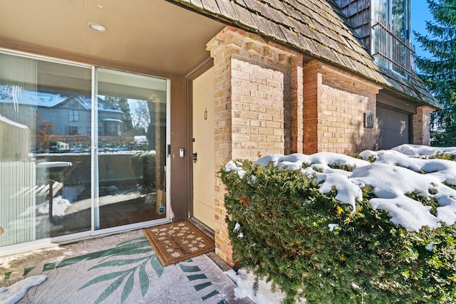 snow covered property entrance with brick siding