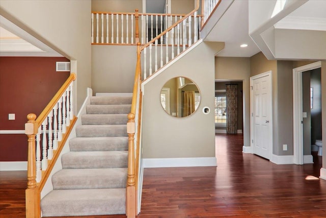 staircase featuring recessed lighting, visible vents, a towering ceiling, wood finished floors, and baseboards