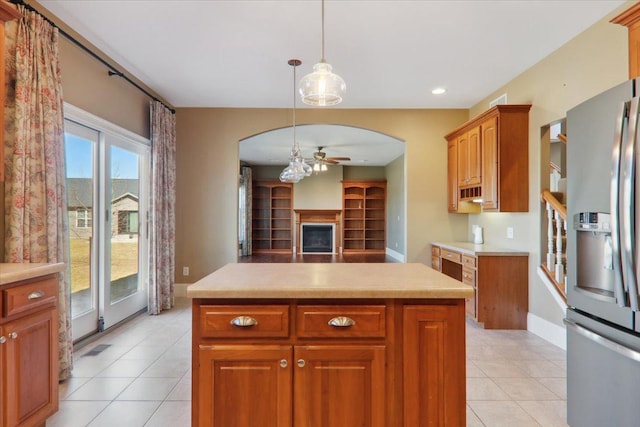 kitchen featuring arched walkways, light countertops, brown cabinetry, ceiling fan, and stainless steel fridge with ice dispenser