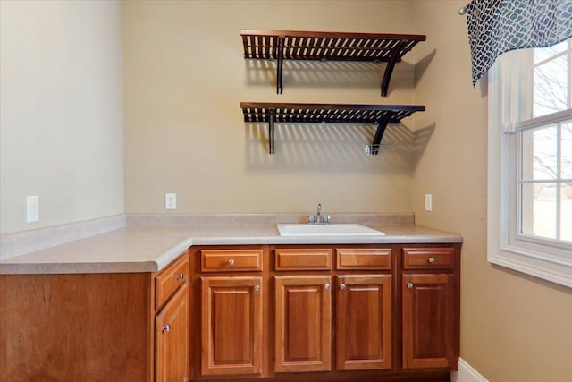 kitchen with light countertops, brown cabinets, and a sink