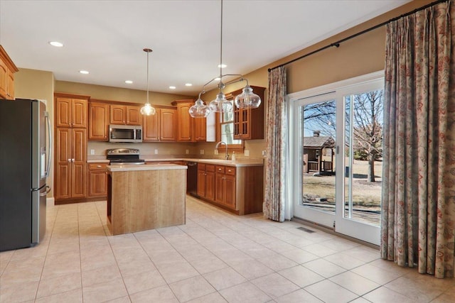 kitchen with a sink, a kitchen island, visible vents, light countertops, and appliances with stainless steel finishes