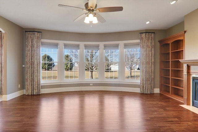 unfurnished living room with a fireplace with flush hearth, baseboards, ceiling fan, and wood finished floors