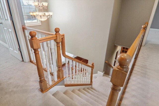 stairway with carpet flooring and an inviting chandelier