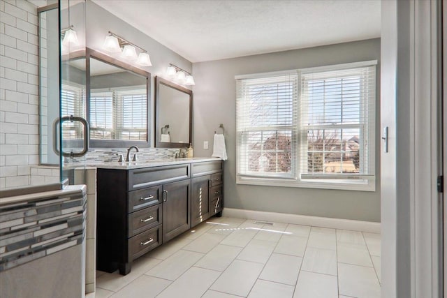 bathroom with a healthy amount of sunlight, a sink, baseboards, and double vanity