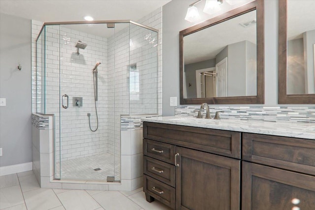 full bath featuring tasteful backsplash, visible vents, a stall shower, vanity, and baseboards