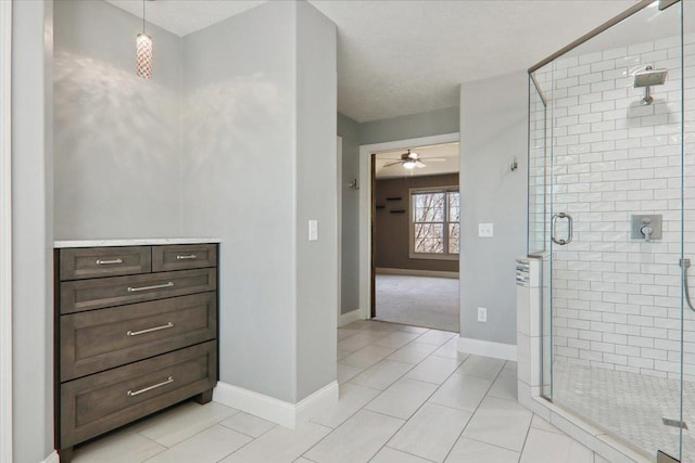 bathroom featuring a stall shower, ceiling fan, baseboards, and tile patterned floors