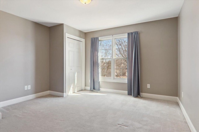 unfurnished bedroom with baseboards, a closet, and light colored carpet