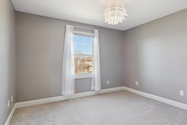 spare room with baseboards, visible vents, and light colored carpet