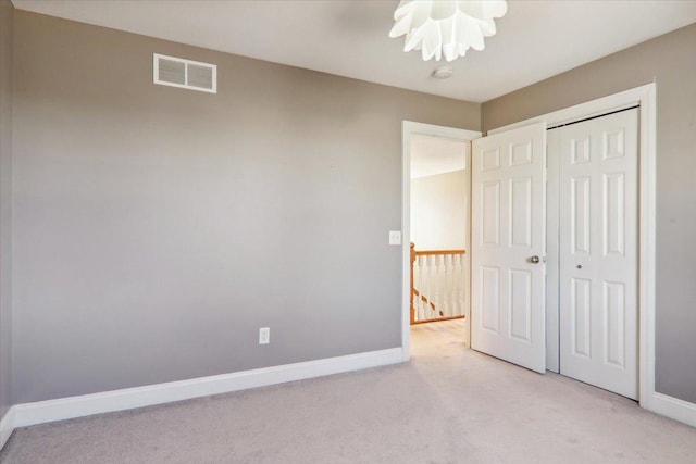 unfurnished bedroom with light carpet, baseboards, visible vents, and a closet