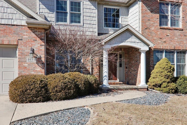 doorway to property with a garage and brick siding