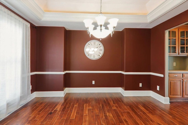 unfurnished dining area with a chandelier, dark wood finished floors, baseboards, ornamental molding, and a raised ceiling